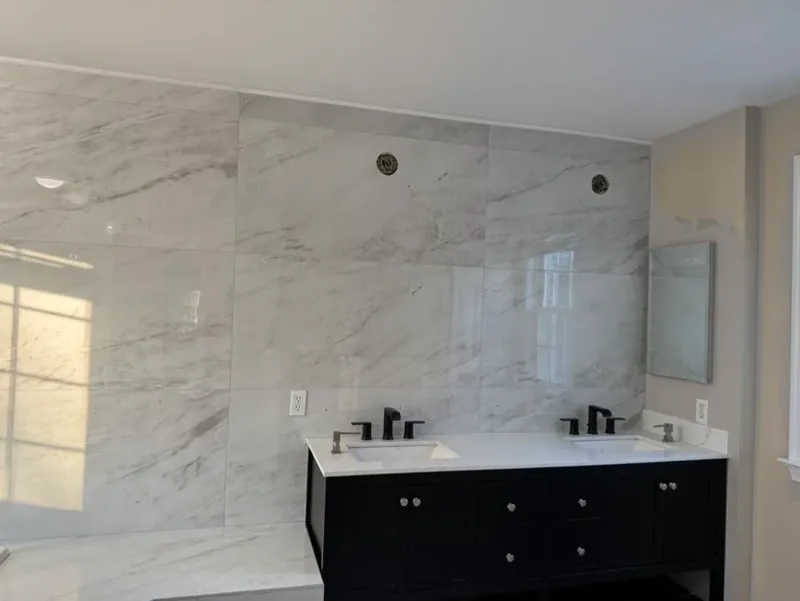 Bathroom wall with white marble-look tile, black vanity, mirror, and recessed lights